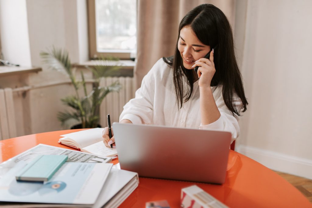 Woman in white dress on business phone call using VoIP phone system 